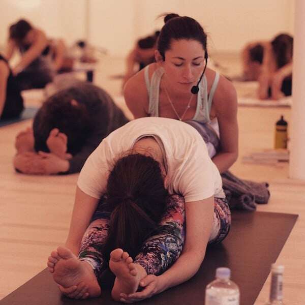 Tara beim Assistieren in Paschimottanasana - Bild via EatTrainLove